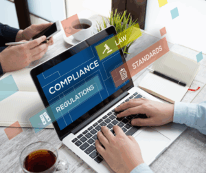 Laptop screen displaying compliance, regulations, law, and standards with a person typing, symbolizing digital compliance management tools.