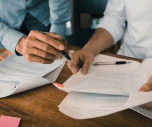 Close-up of two people reviewing printed documents with pens, symbolizing verification and protection of research records.