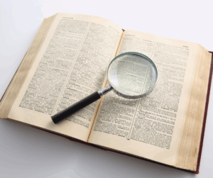 Magnifying glass placed over the pages of an open book, symbolizing close examination and verification of research details.