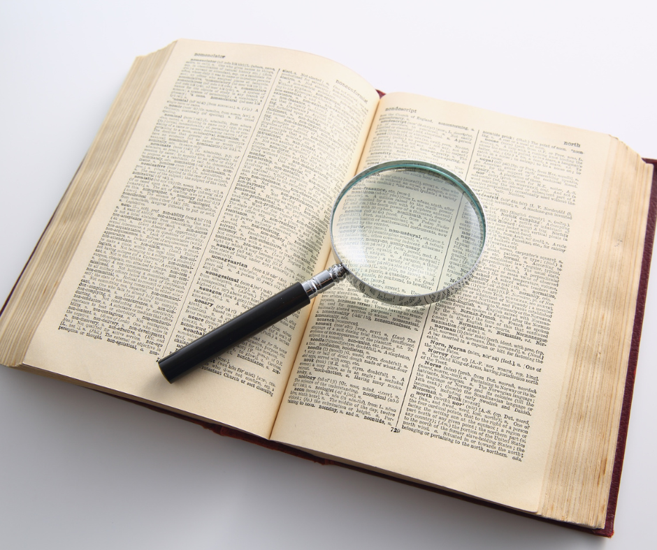 Magnifying glass placed over the pages of an open book, symbolizing close examination and verification of research details.