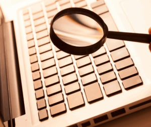 Magnifying glass placed over the pages of an open book, symbolizing close examination and verification of research details.